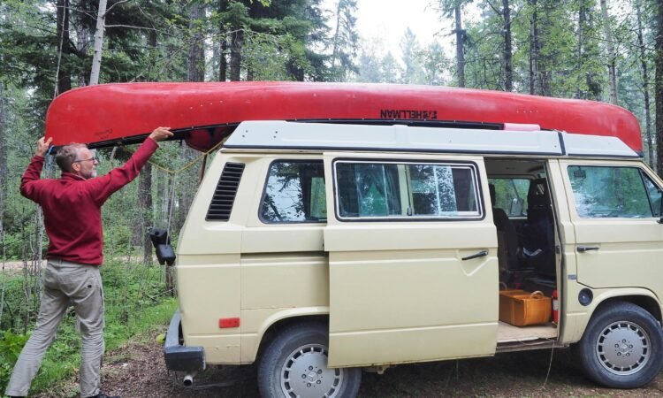 un homme qui met son canoë sur le toit de son van